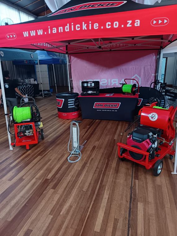 A supplier stand displaying drain jetting machines on the wooden floor of an exhibition hall